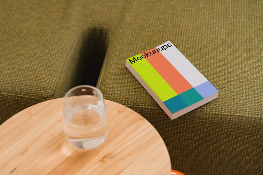 Paperback book mockup on a cozy green sofa